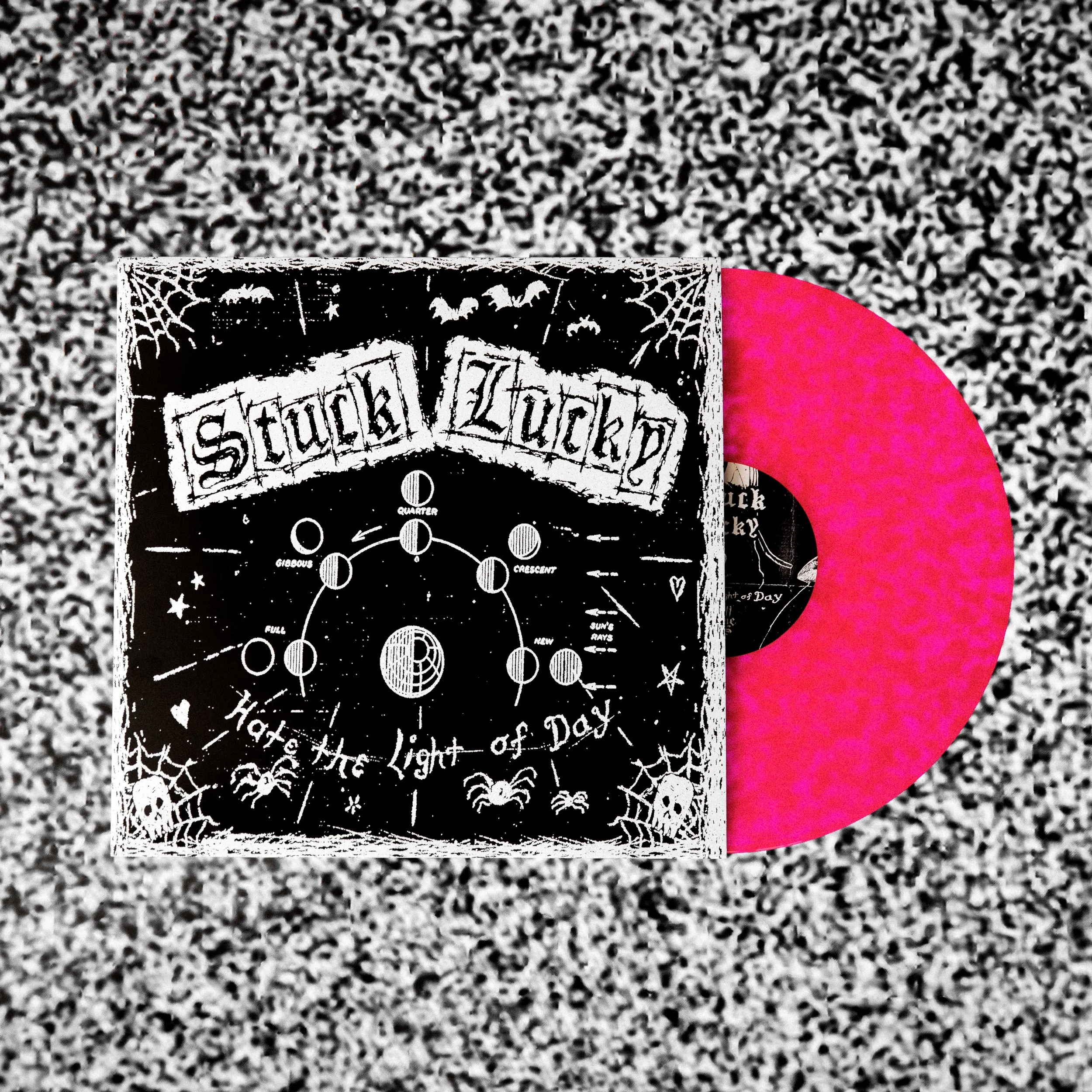Pink vinyl record with black and white cover art featuring Halloween-themed illustrations and the text 'Stuck Lucky' and 'Hate the Light of Day'.