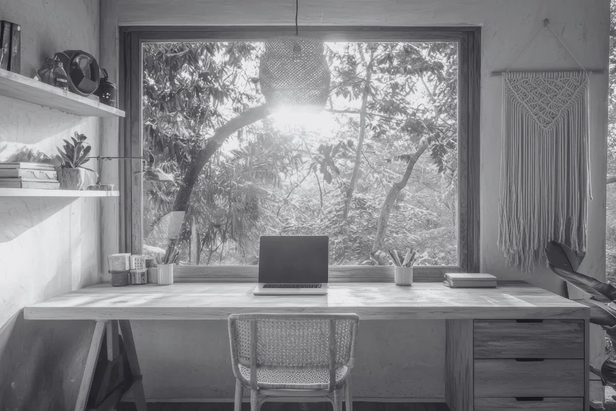 Een werkplek met een laptop op een tafel voor een groot raam.