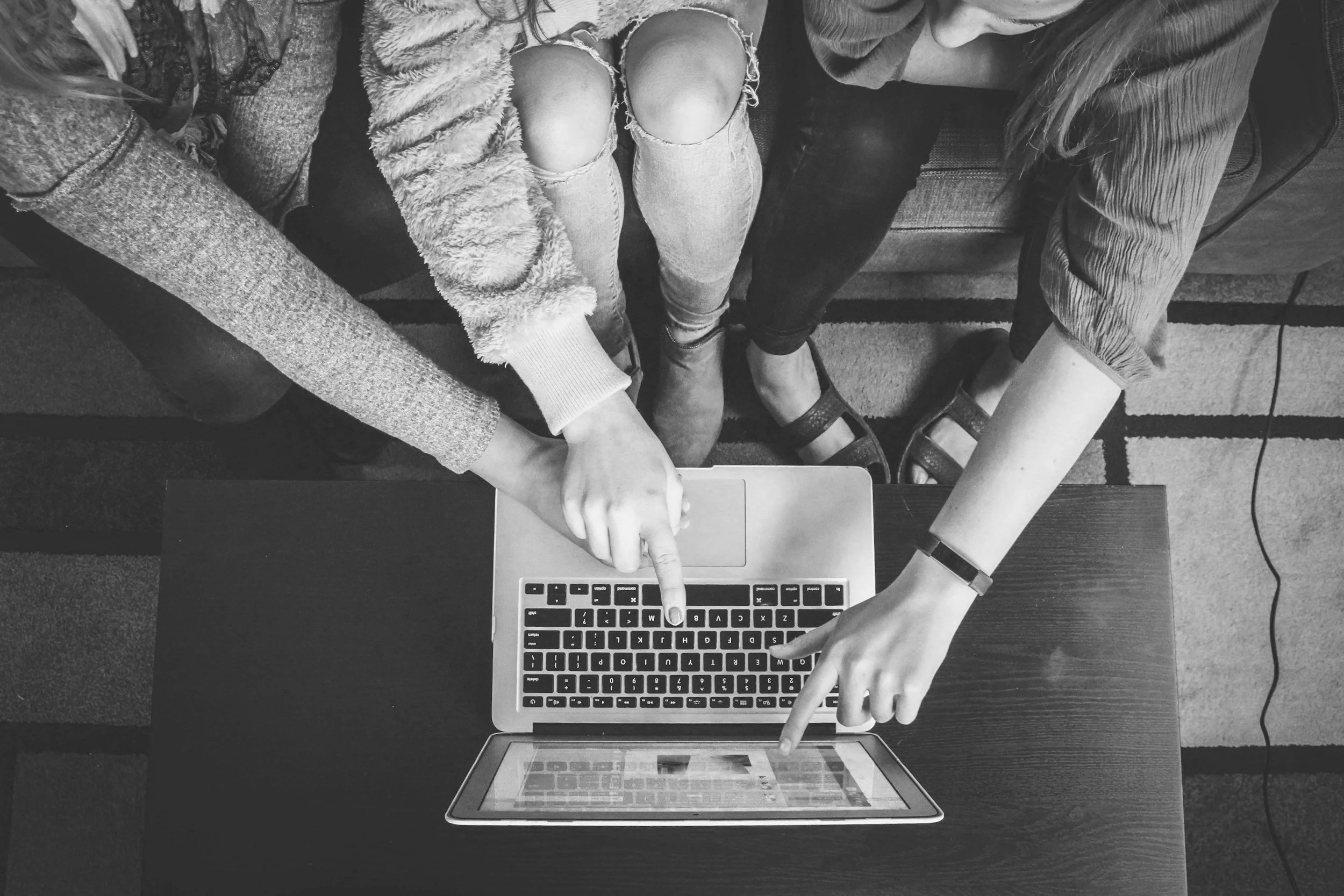 Drie vrouwen werken samen aan een tafel met een laptop.