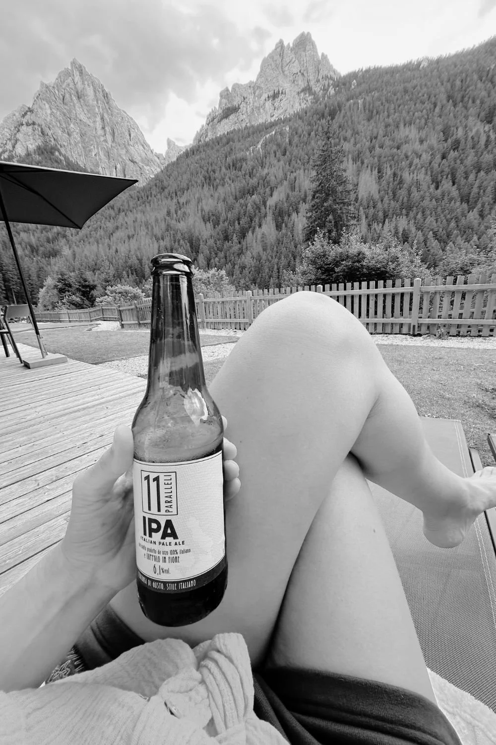 Benen op een ligstoel met een biertje, met bergen op de achtergrond.