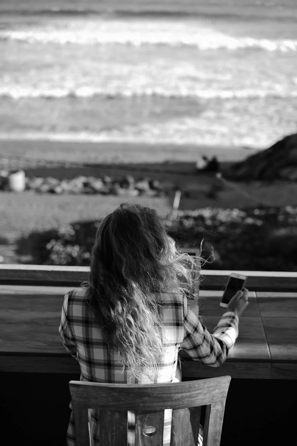 Een vrouw, gezien van achteren, werkt met een laptop aan een tafel.