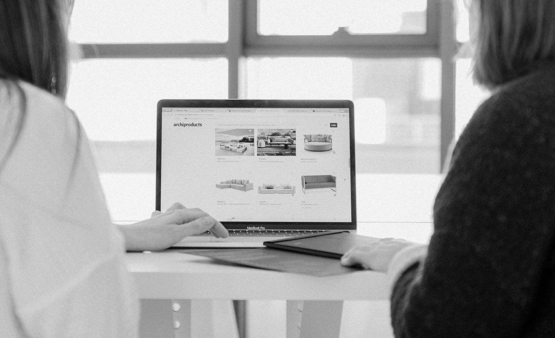 Twee personen, gezien van achteren, zitten samen achter een computer.