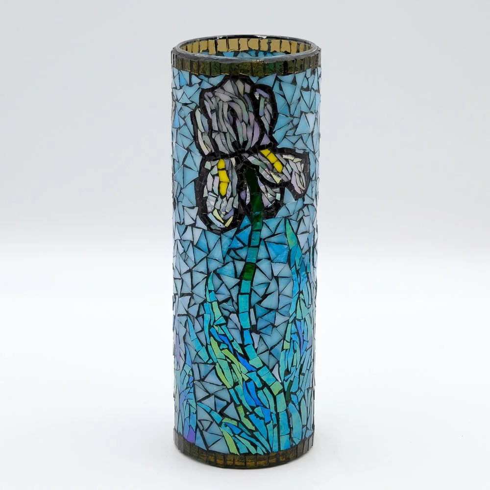 A cylindrical mosaic glass lamp with a painted butterfly and flower design in shades of blue, purple, yellow, and green.