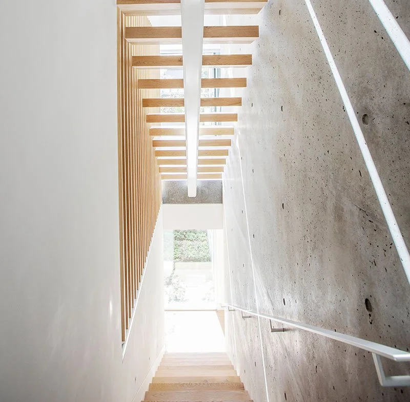 Modern interior with concrete walls, wooden slats, and natural light from large windows.