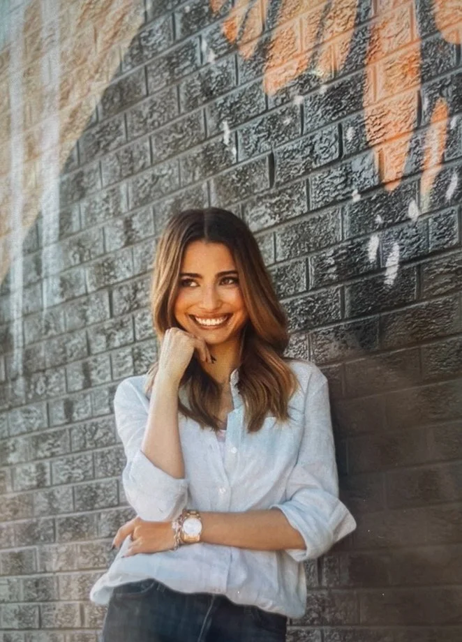 Boulder-based Founder of Lovers Counseling, Chloé (Chloe) Miller smiling in front of black brick wall.