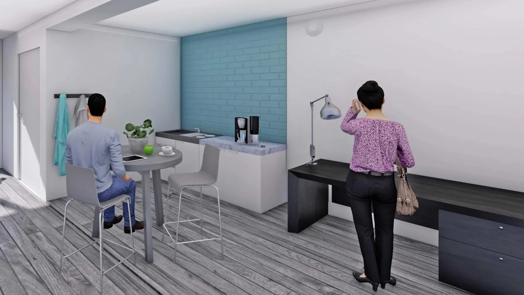 A modern kitchen with a man seated at a high table and a woman standing near a desk, talking on the phone, with a blue accent wall and grey wood flooring.