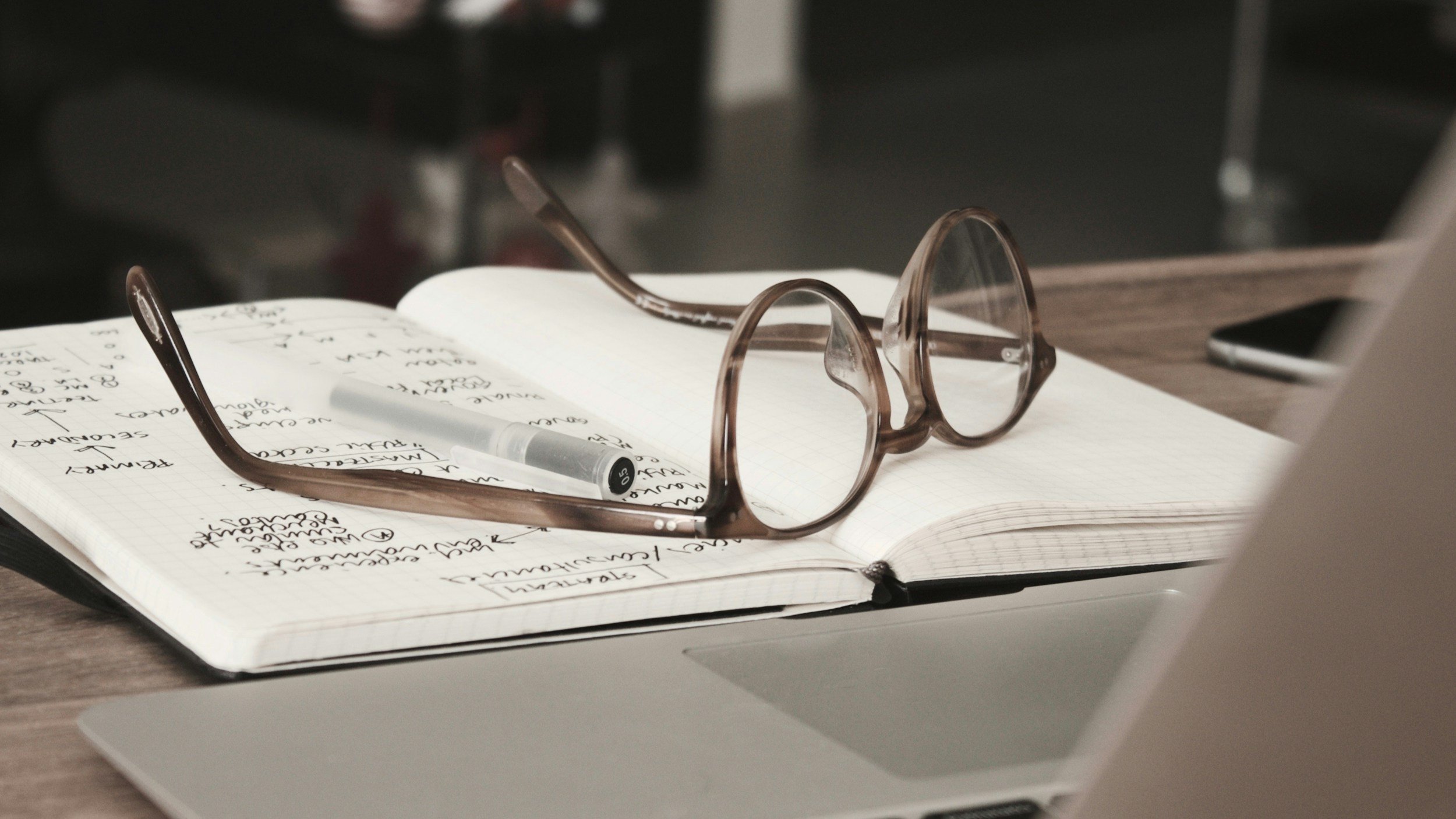 Brown glasses upturned on a notebook representing the due diligence required in sustainability statements and planning compliance documents.