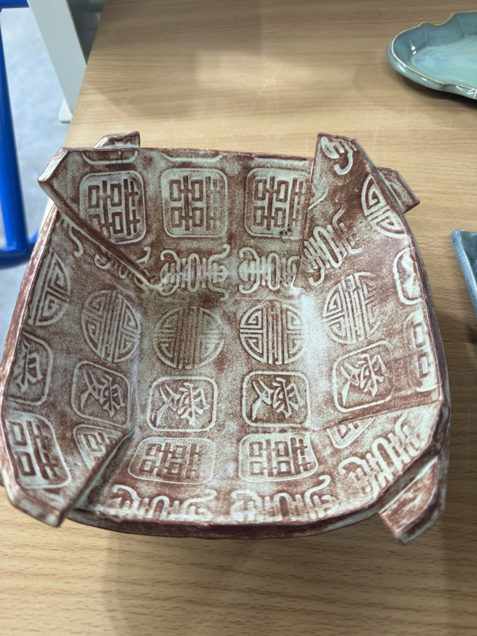 A brown paper takeout container with Chinese-style decorative patterns inside, placed on a wooden surface.