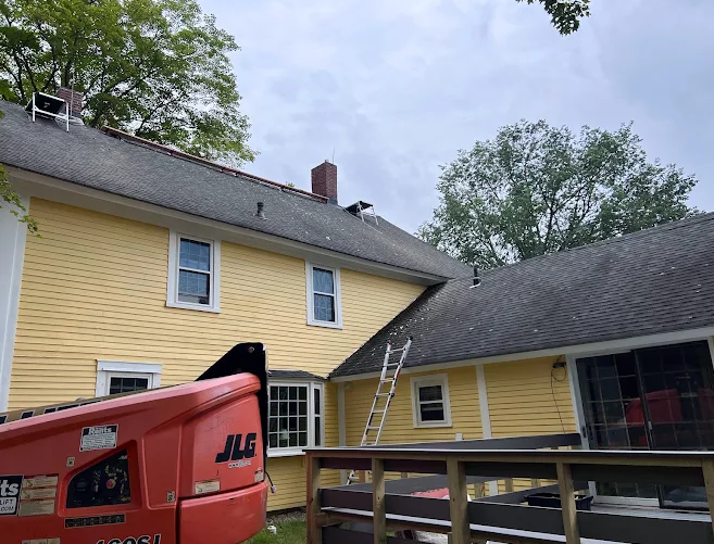 residential chimney repair featuring a yellow house with ladder propped up on roof