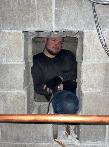 professional chimney sweeper and founder of Granite State Chimney sitting inside a chimney in Londonderry, NH