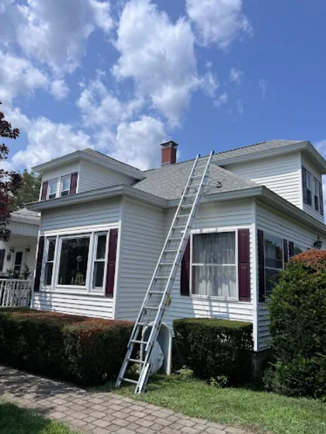 ladder propped up on roof of white house for residential chimney repair services