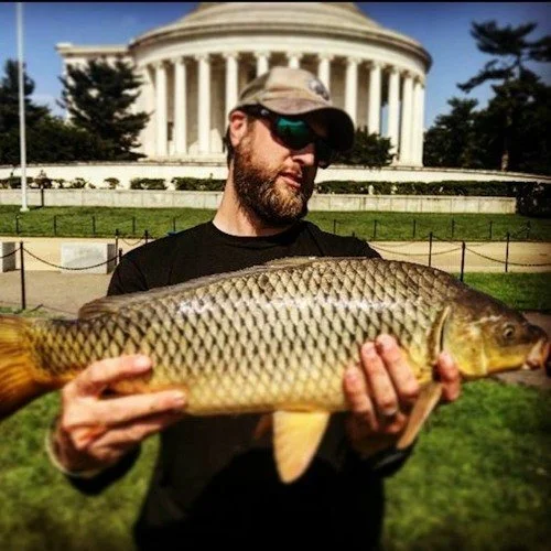 Man holding a large fish in front of the Lincoln Memorial in Washington, D.C.