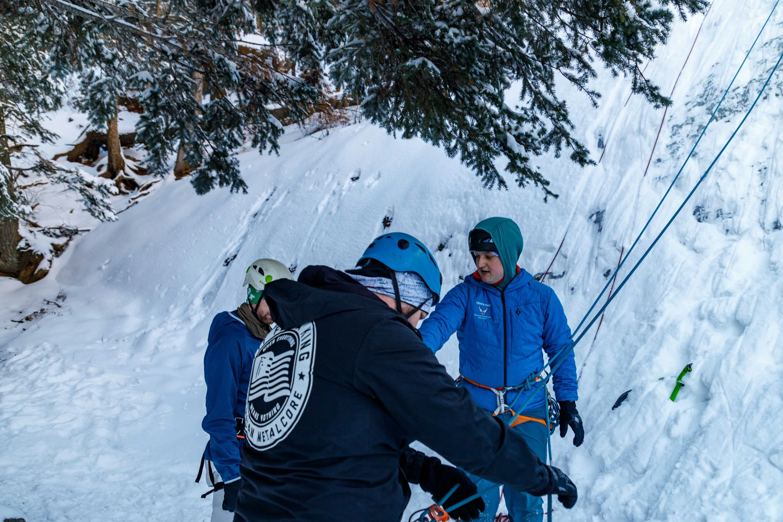 Group of hikers adjusting equipment in snowy forested area during winter.
