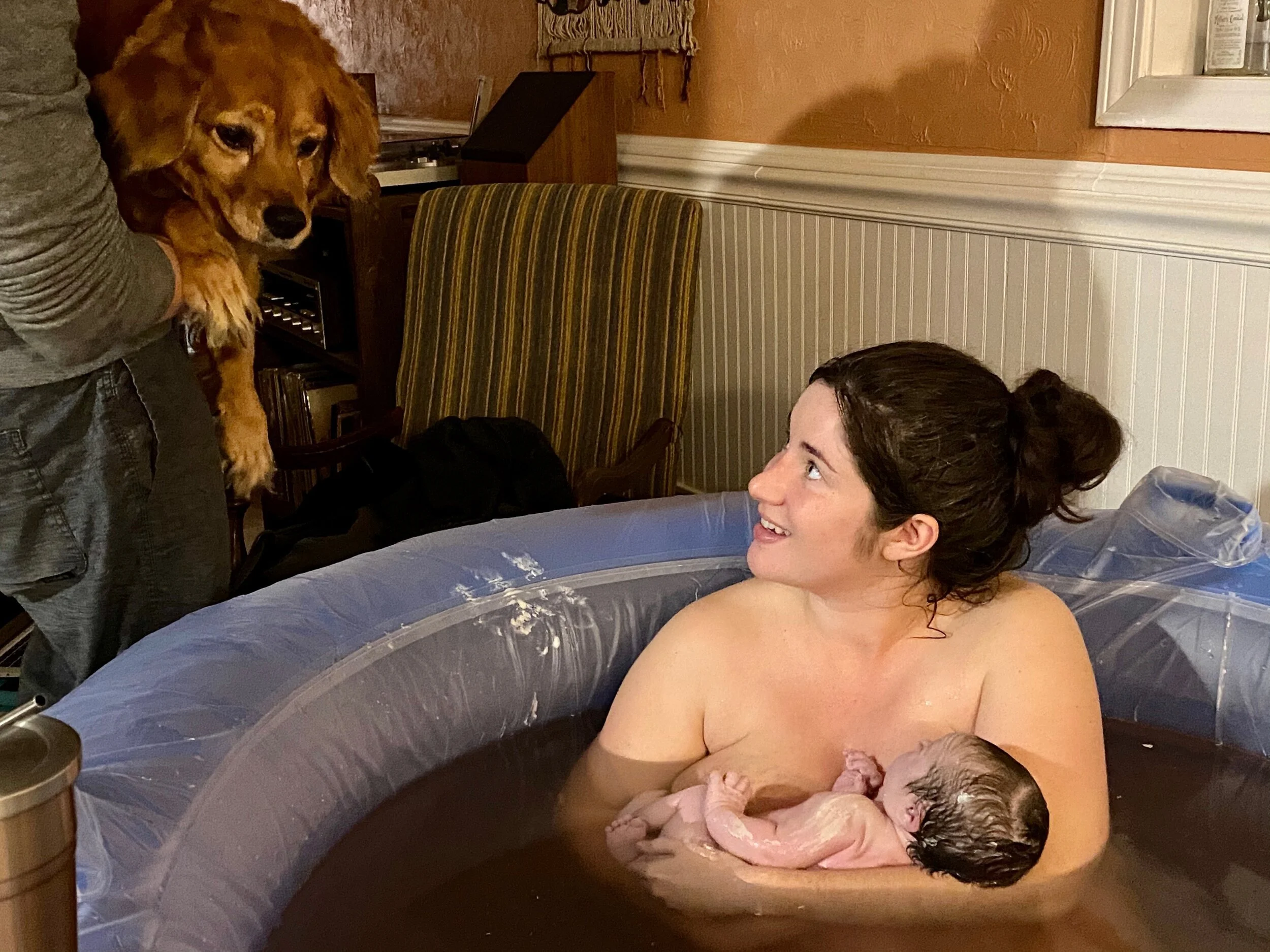 mother smiles after home birth in water with healthy newborn