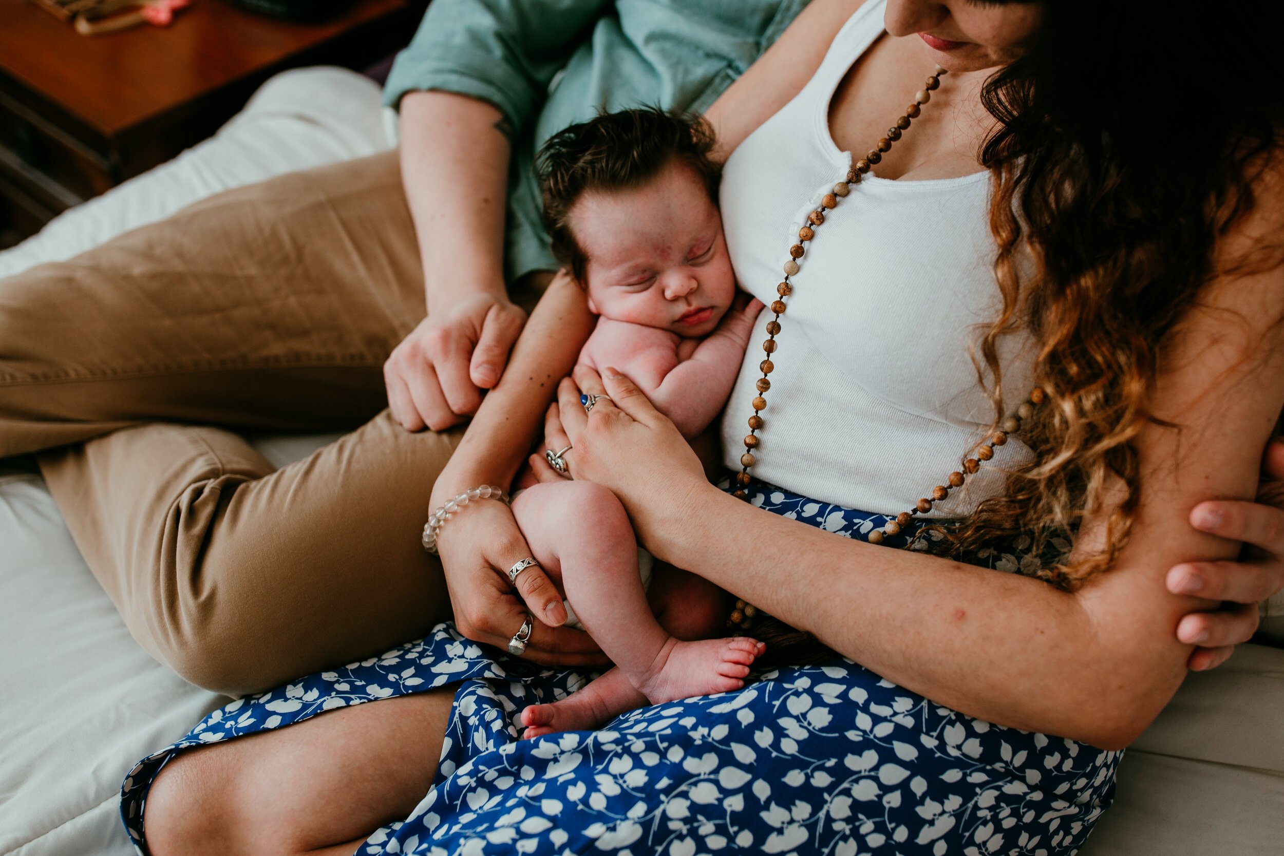 new parnets snuggle baby in arms at home newborn photos