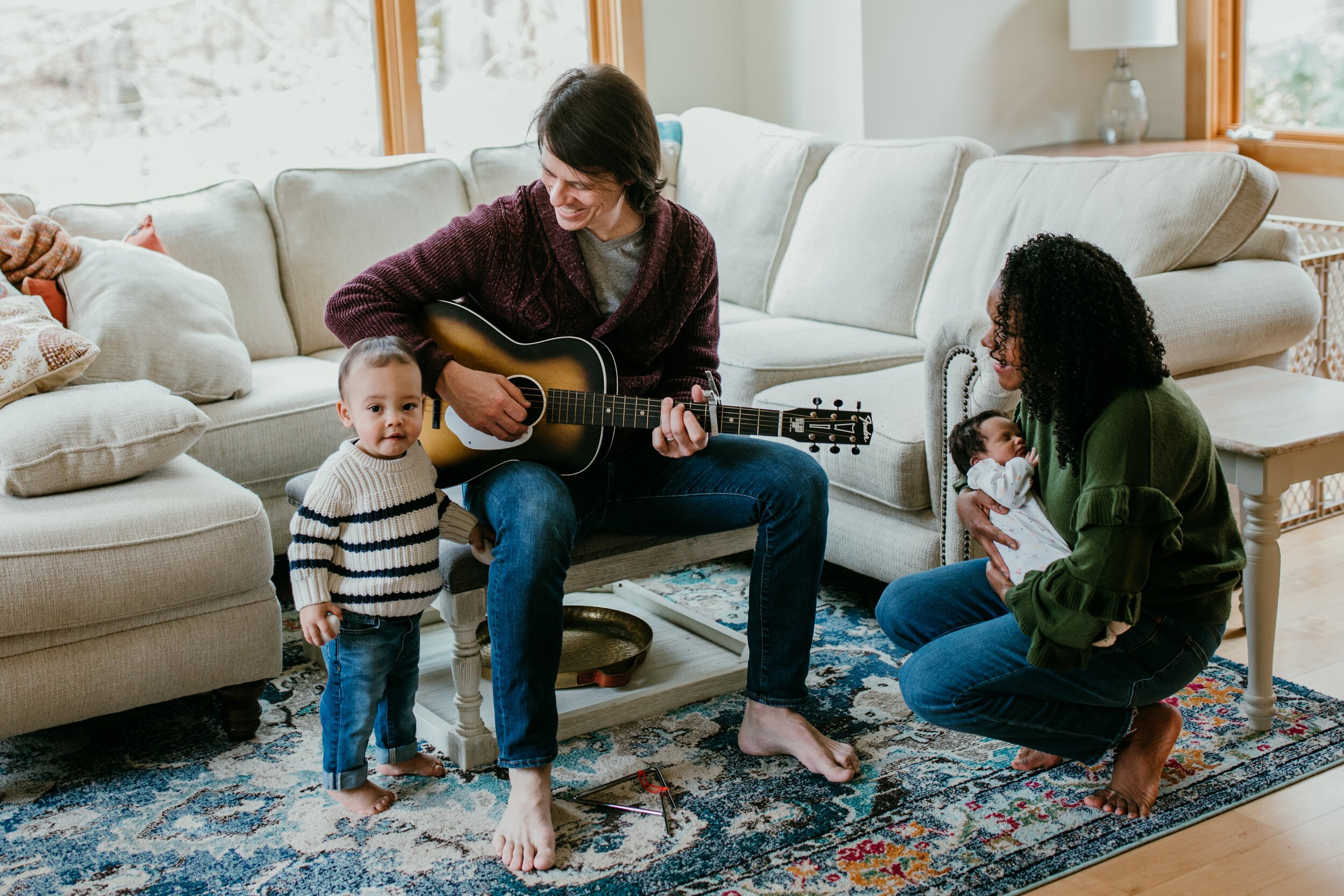 family of four sit together in living room playing music 