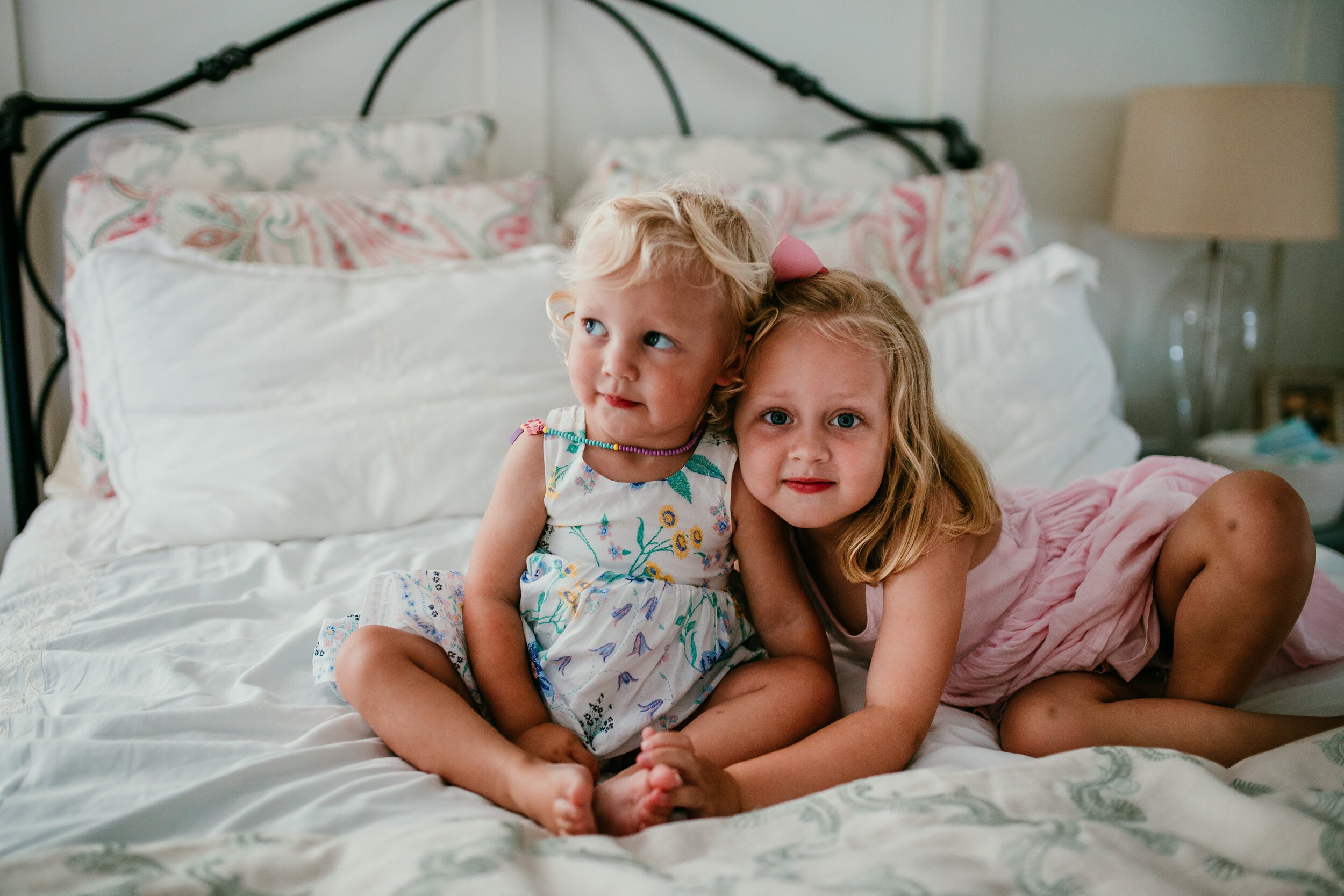sisters snuggle on bed in home family session 