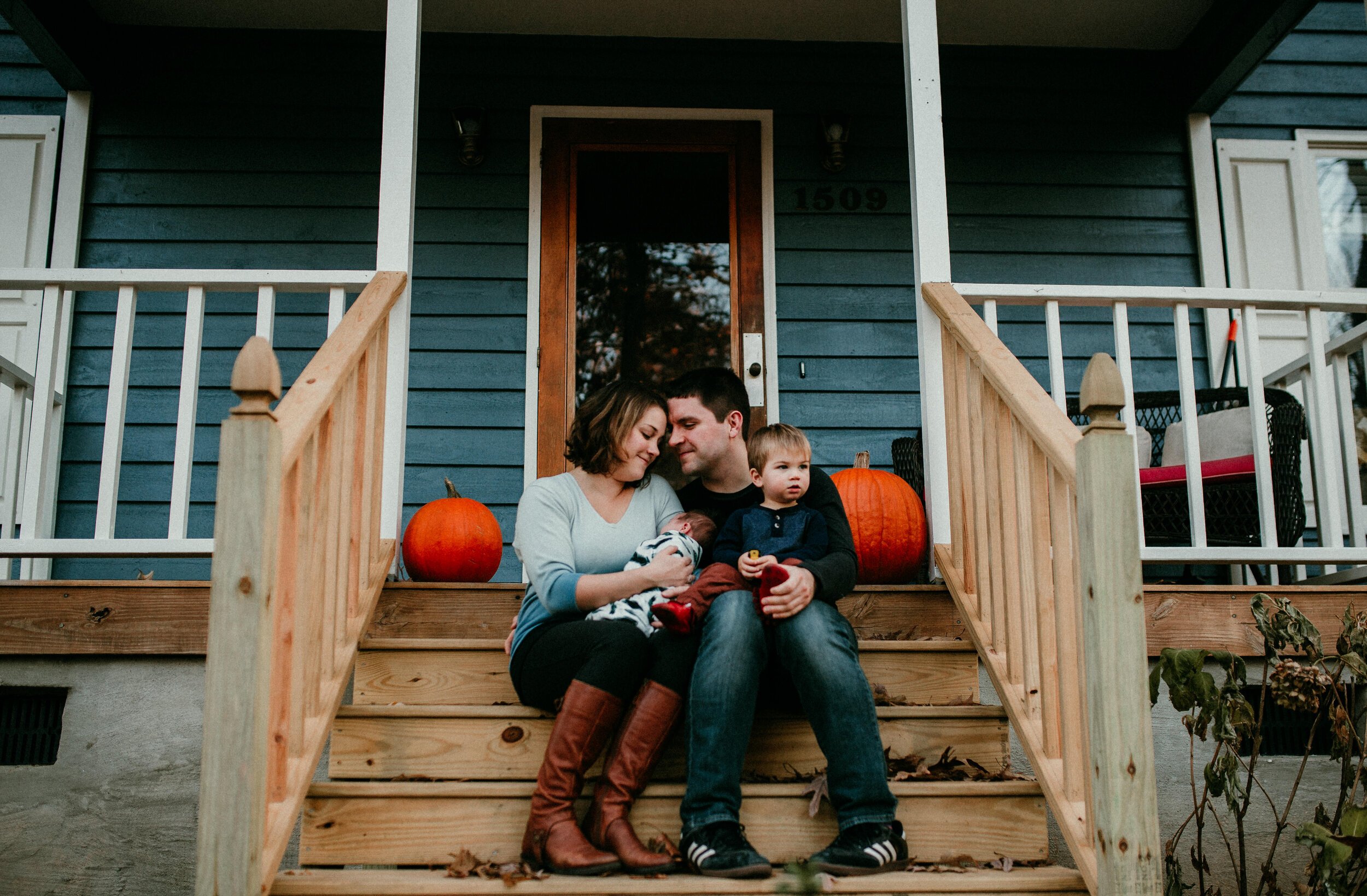 family snuggles newborn on front porch of Durham England home 