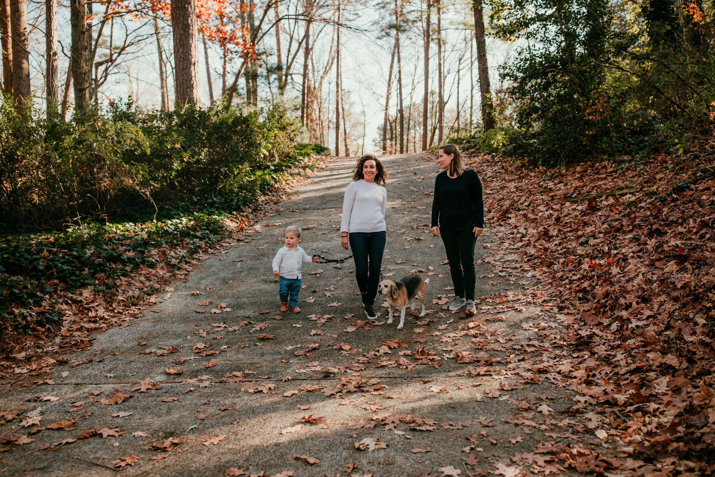 two mothers walk with son and dog down their driveway in the Fall