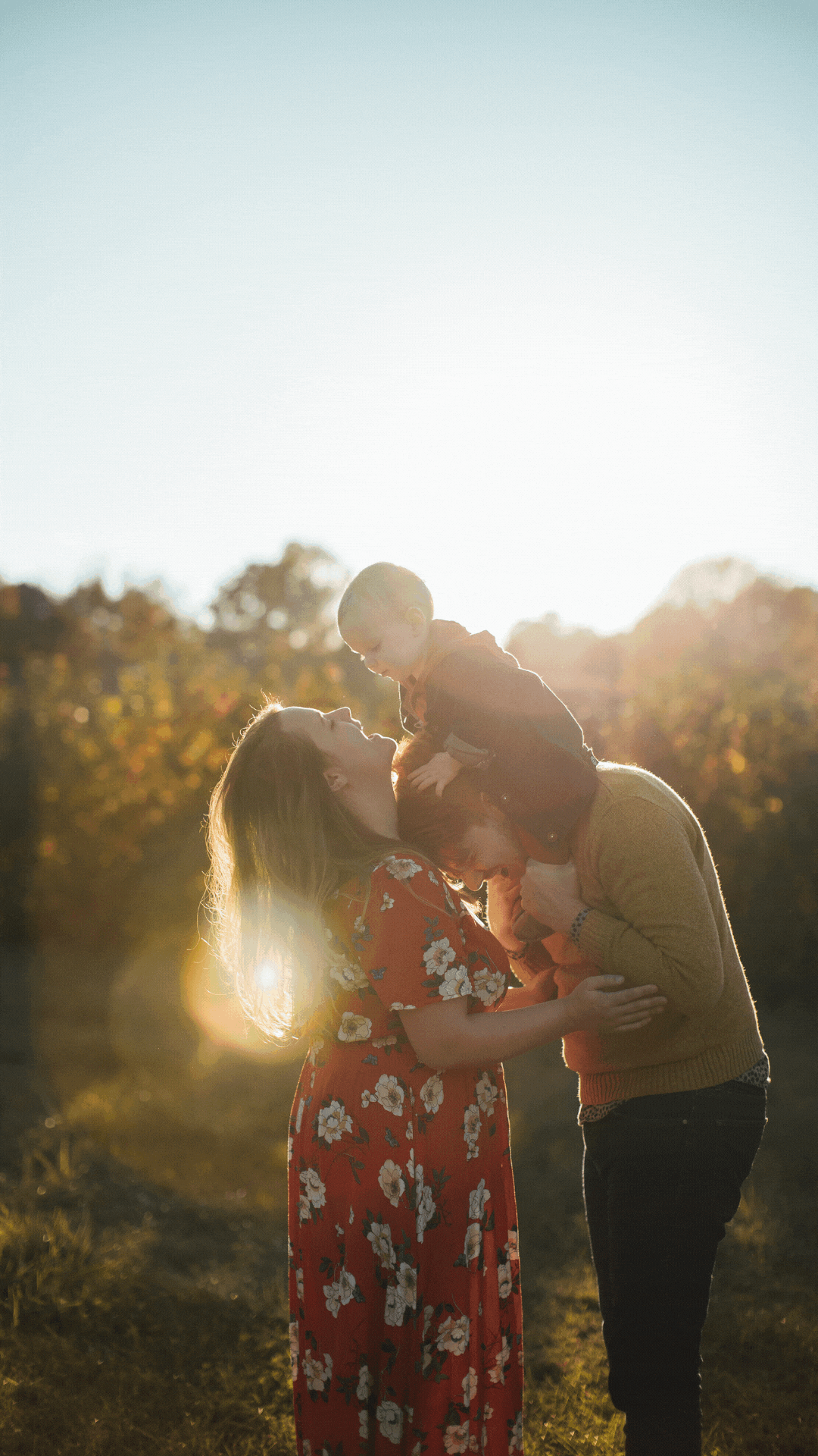 family of three stand together with beams of light coming through