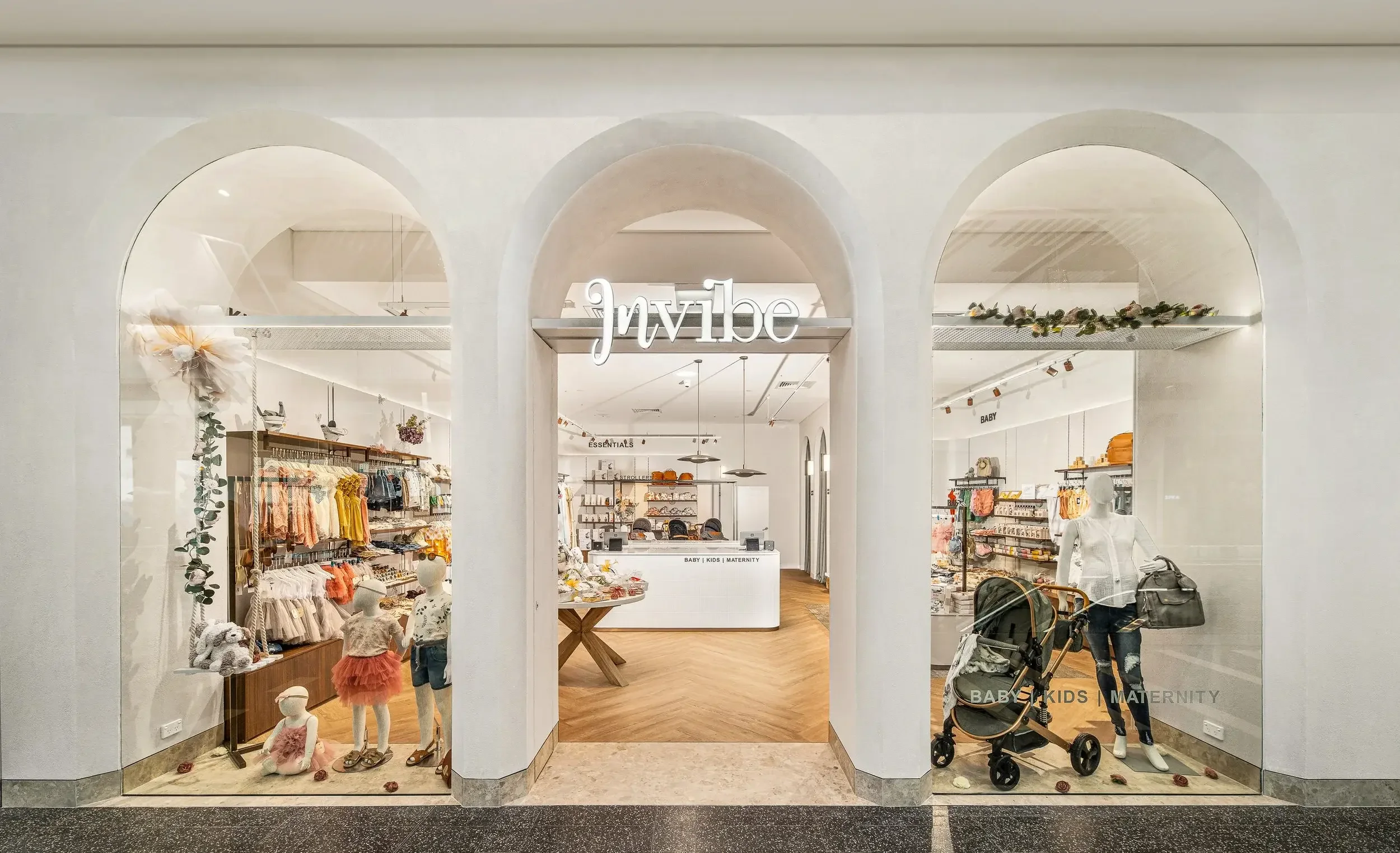 Storefront of a children's clothing and maternity shop with mannequins, clothing displays, and a checkout counter in the background.