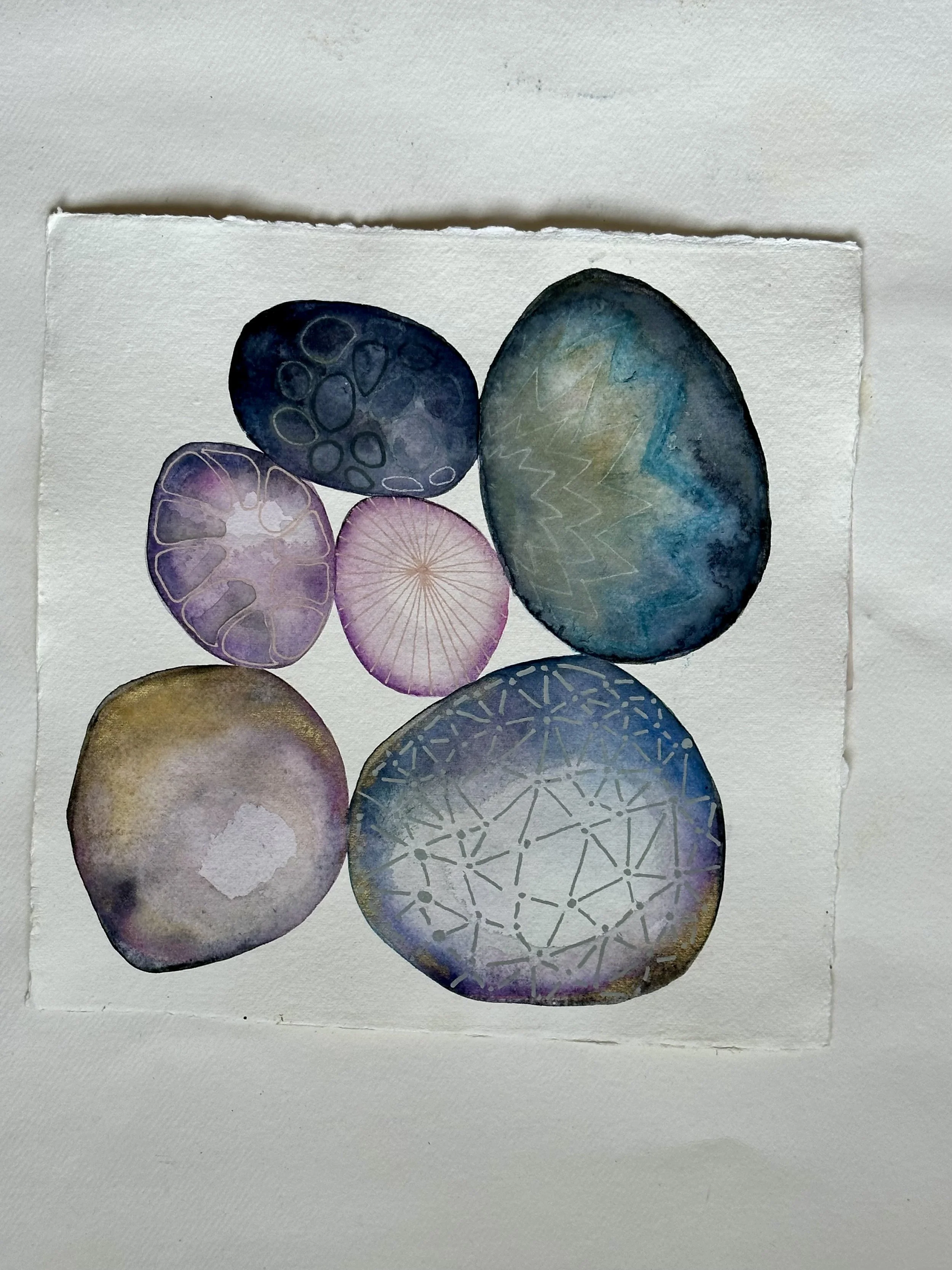Abstract watercolor painting of various rocks with geometric patterns on paper.