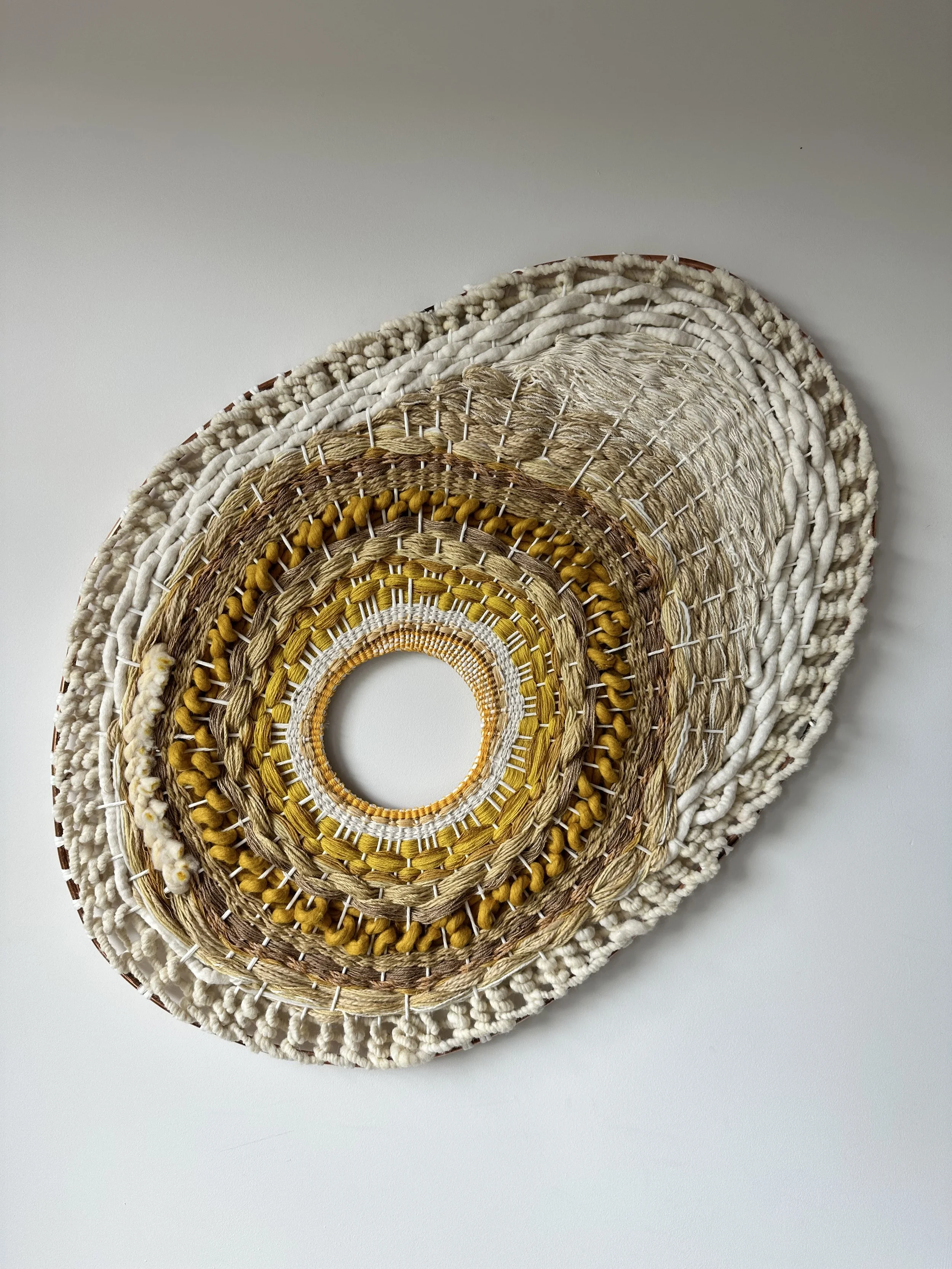 Woven wall hanging with circular pattern and natural fibers