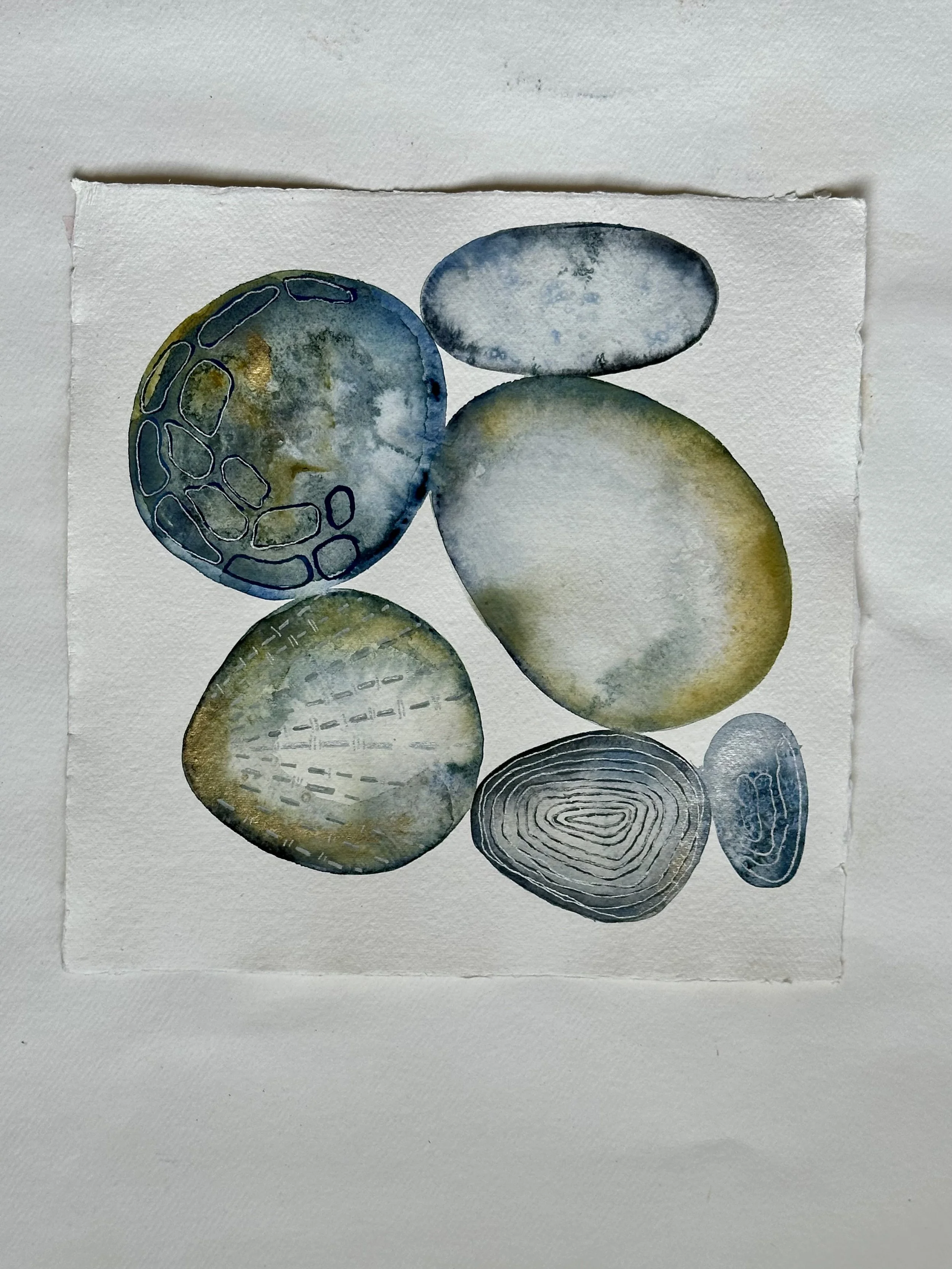 Watercolor painting of abstract stones with various textures and colors, including shades of blue, green, and gray, on a white background.