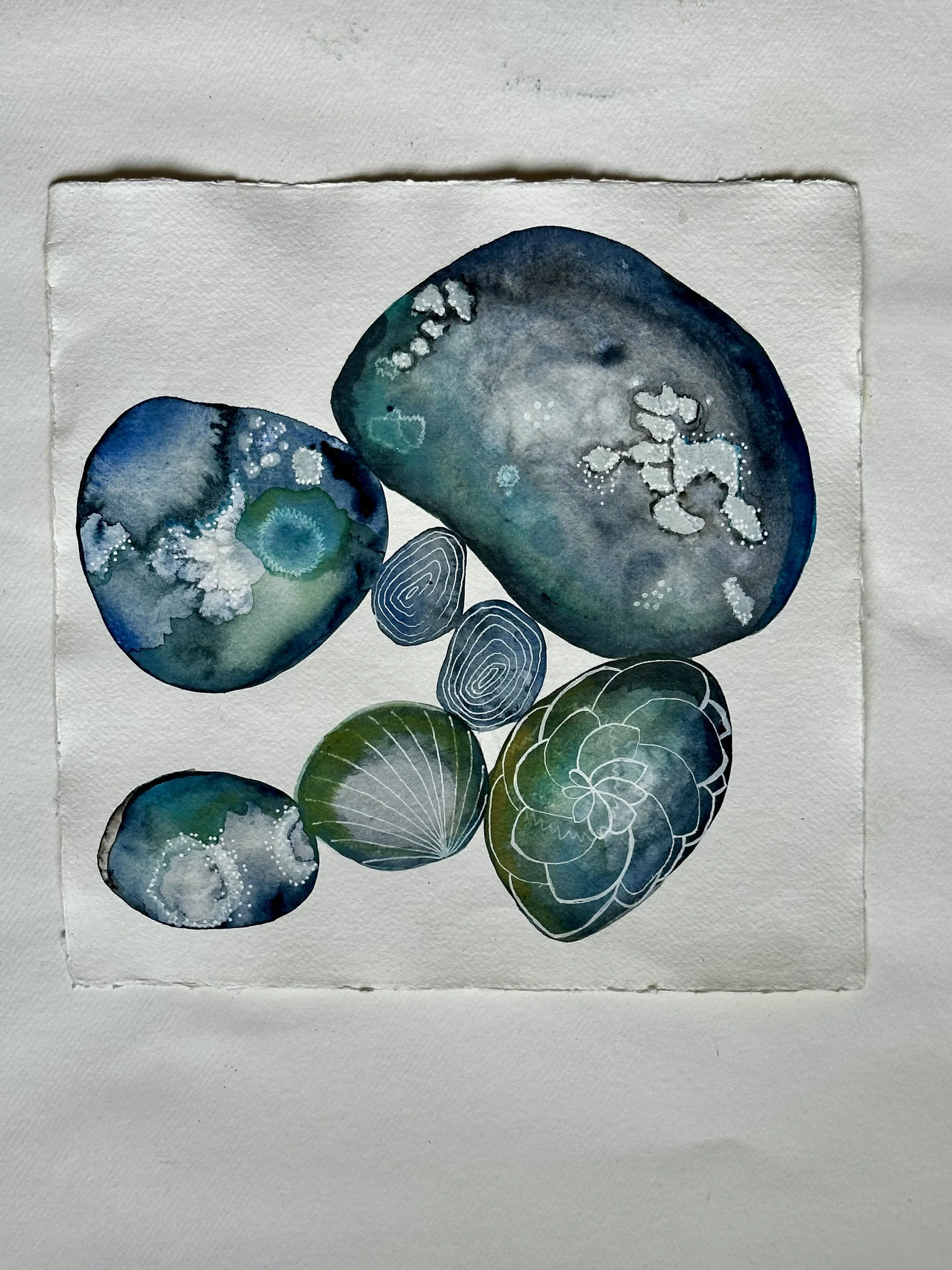 Abstract watercolor painting featuring rocks and shells in shades of blue and green.