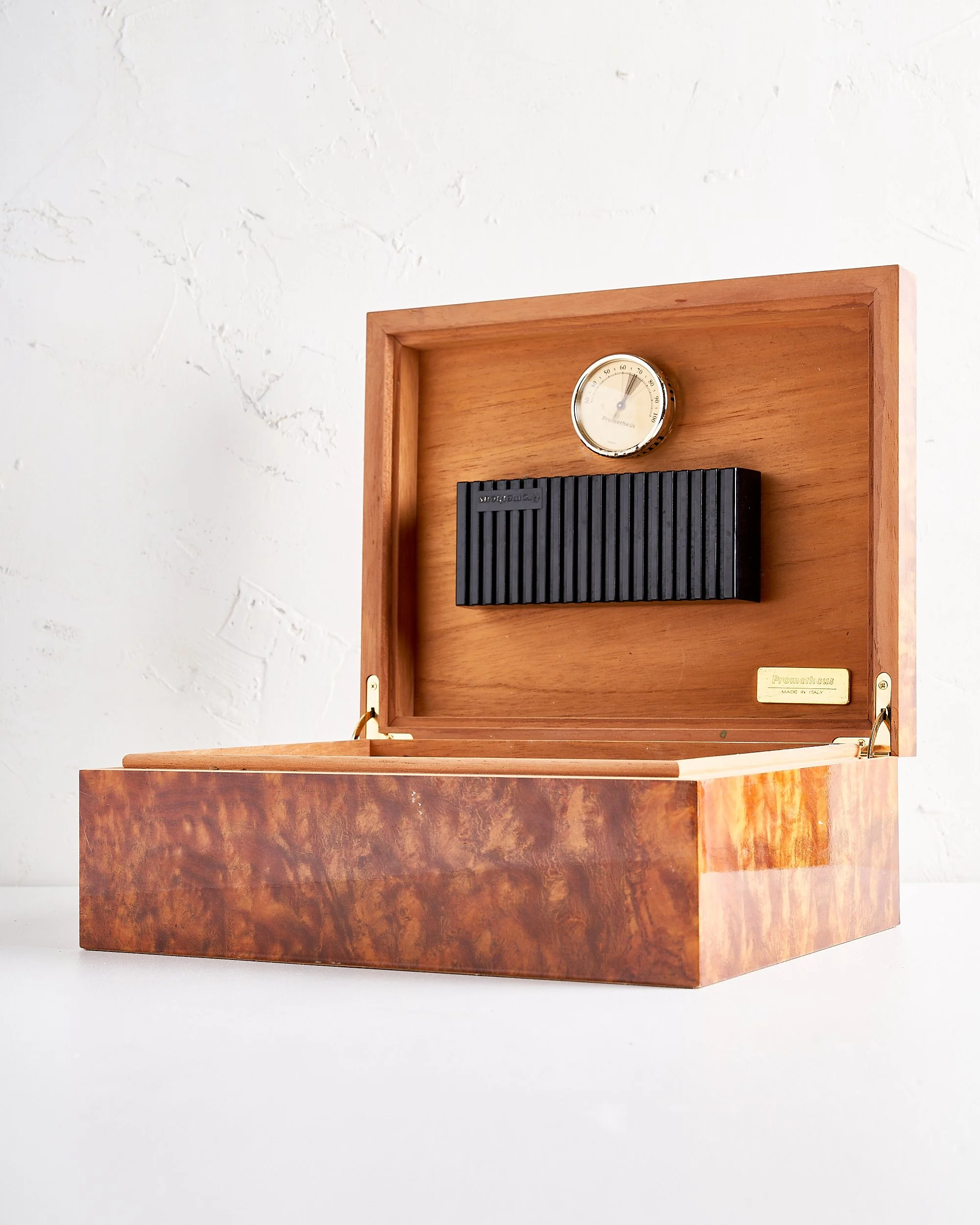 Vintage wooden cigar humidor with a hygrometer, a black vented humidifier, and a brass nameplate inside the lid