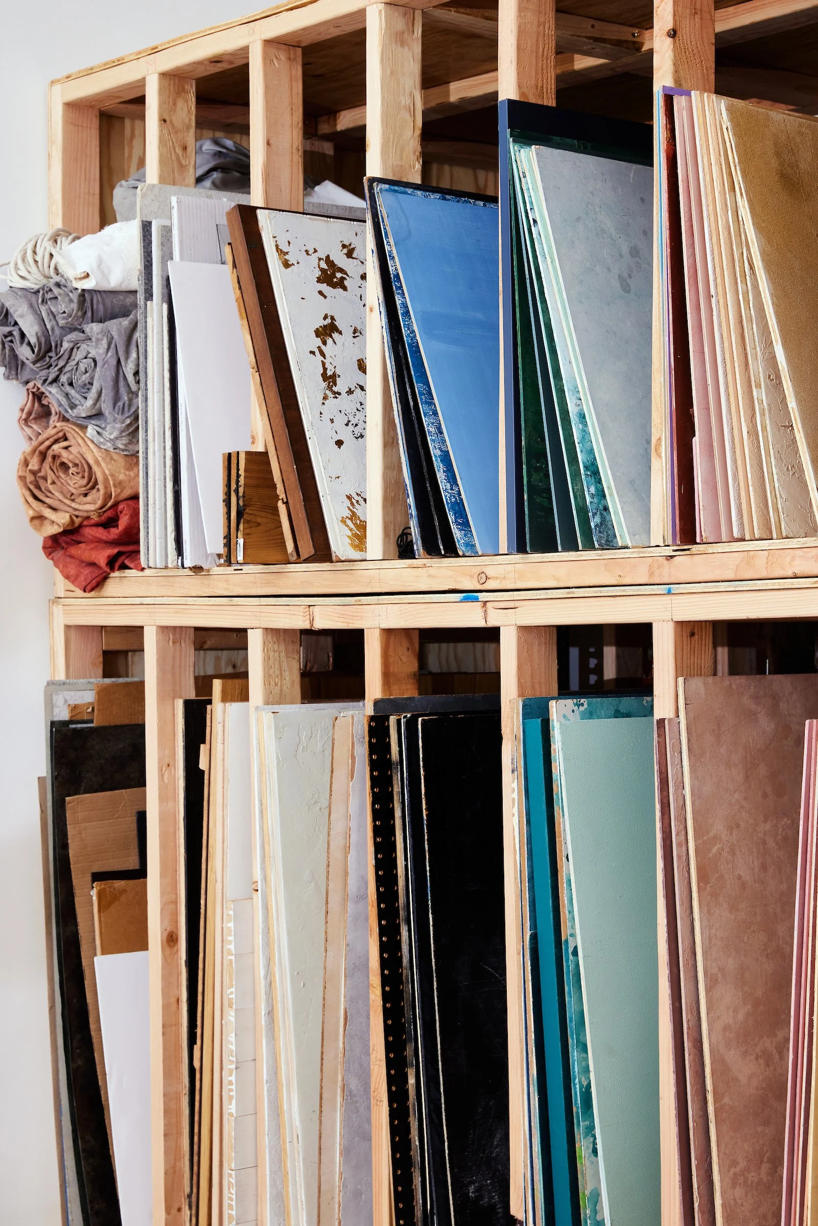 Various large photo surfaces, canvases and fabric backdrops organized in a wooden storage rack.