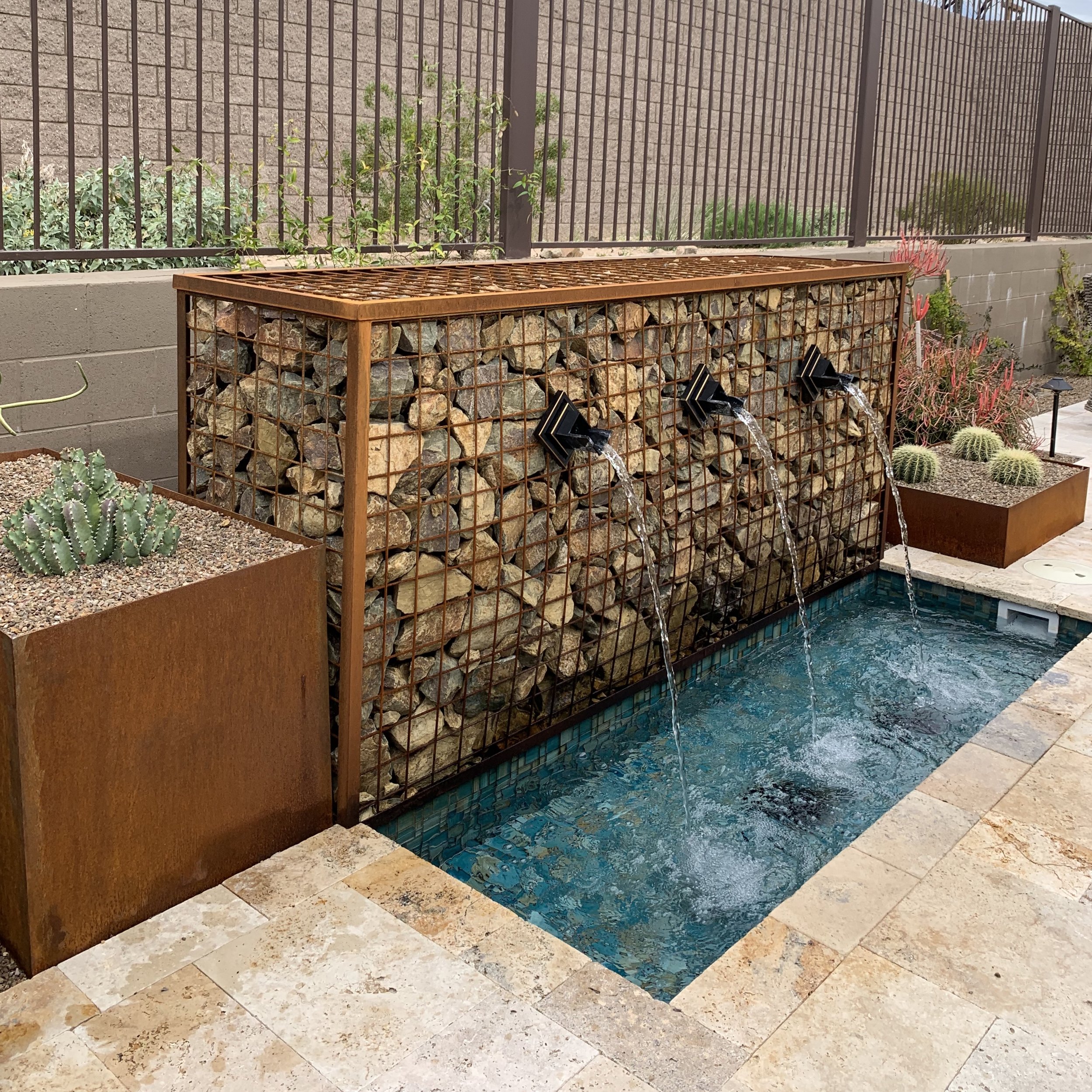 caged stone rusted metal water feature scuppers layered planters