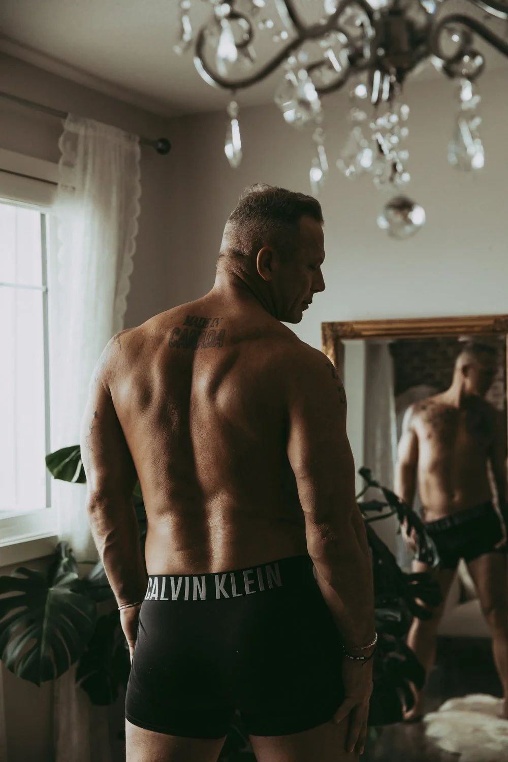 A man standing in front of a mirror posing during a male boudoir photography session in Edmonton