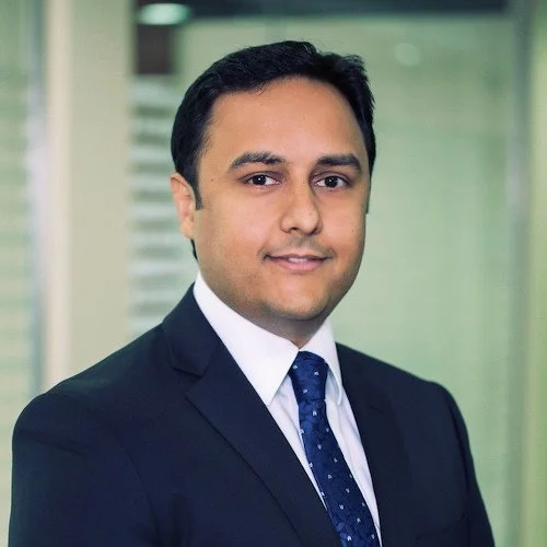 Professional man in suit smiling in office setting.