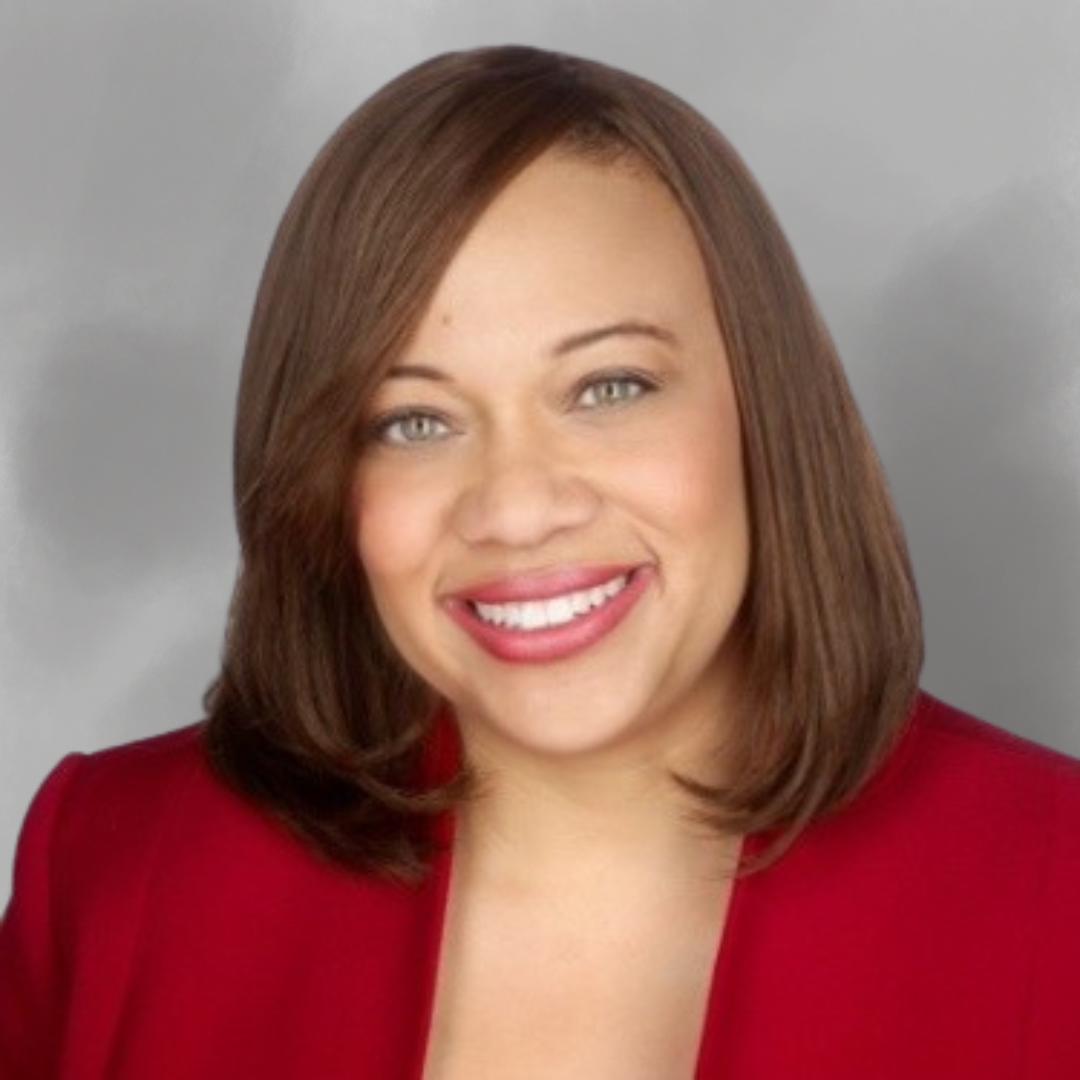 Professional headshot of a smiling woman with shoulder-length brown hair, wearing a red blazer and pink lipstick, against a neutral gray background.