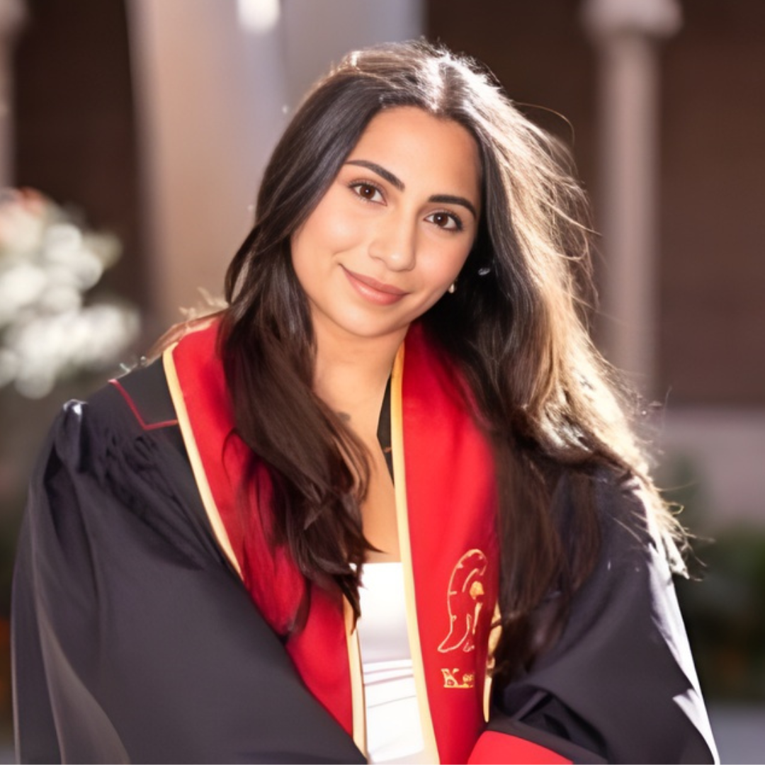 A young woman dressed in a graduation gown with a red and black hood, smiling at the camera.