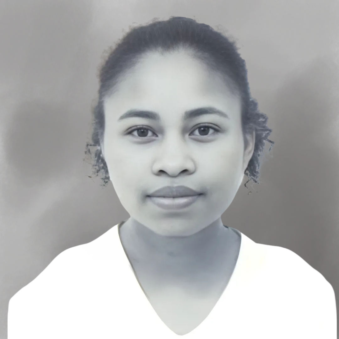 A young woman with curly hair tied back, wearing a white top, facing the camera with a neutral expression.