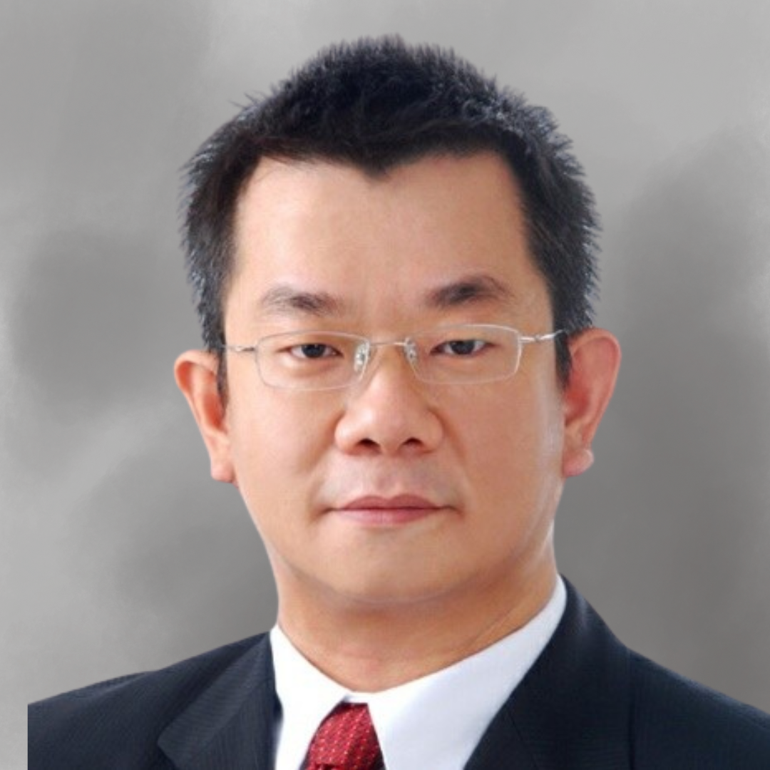 A portrait of an East Asian man with short black hair, glasses, wearing a dark suit, white shirt, and red tie, against a gray background.