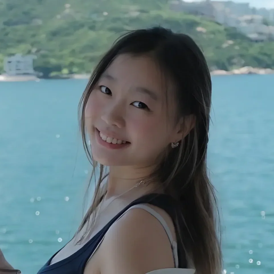 A young girl smiling, with waterfall and mountains in the background.