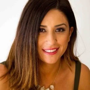 Close-up of a woman with long dark hair smiling at the camera.