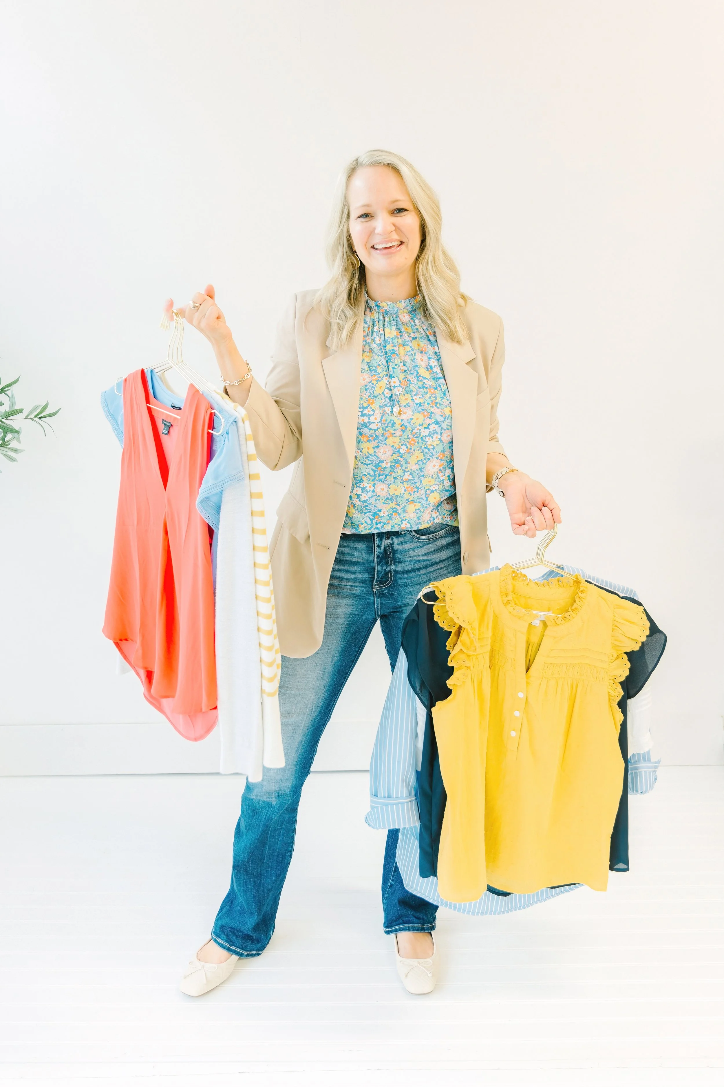 Laura Longmire stands with a number of articles of clothing ready to help you as a personal wardrobe stylist in San Antonio.