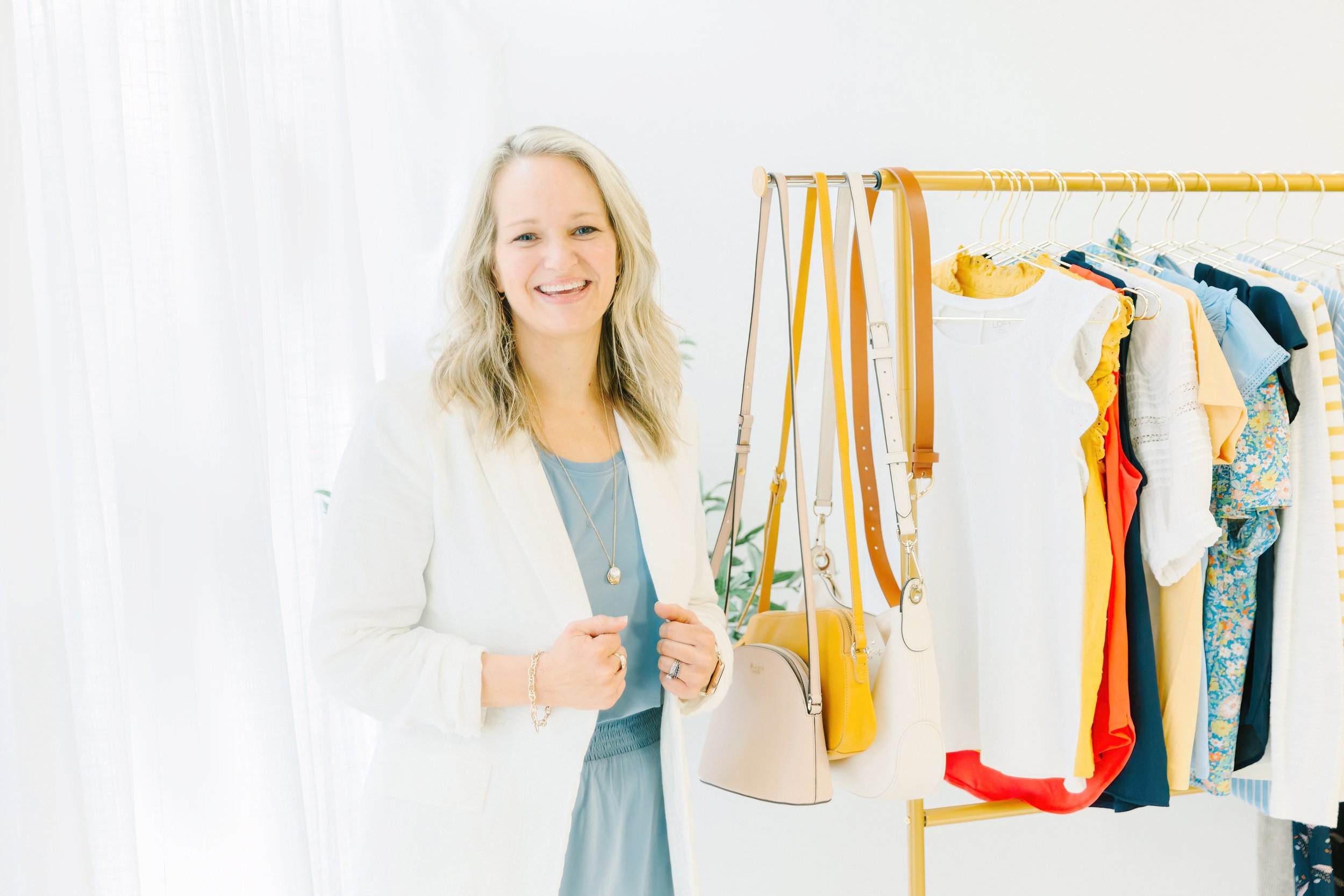 San Antonio personal wardrobe stylist Laura Longmire smiles as she stands next to clothes she has put together for outfits