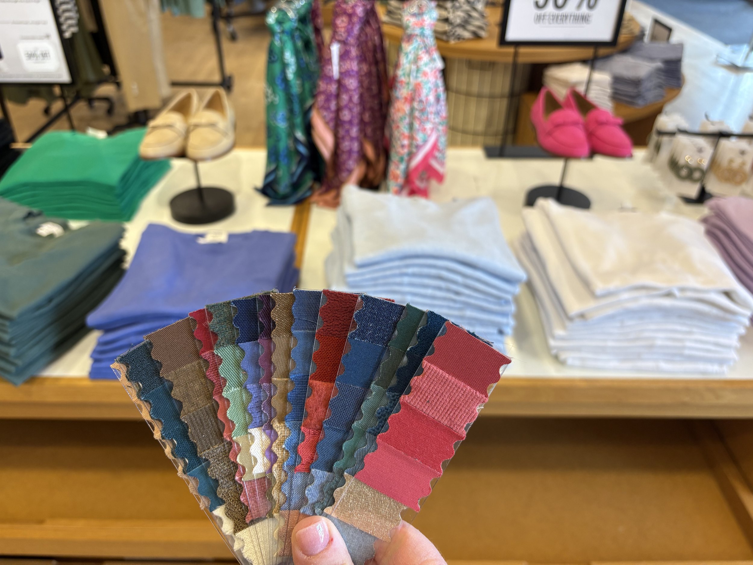 Fabric swatch fan held in front of clothes in store in San Antonio