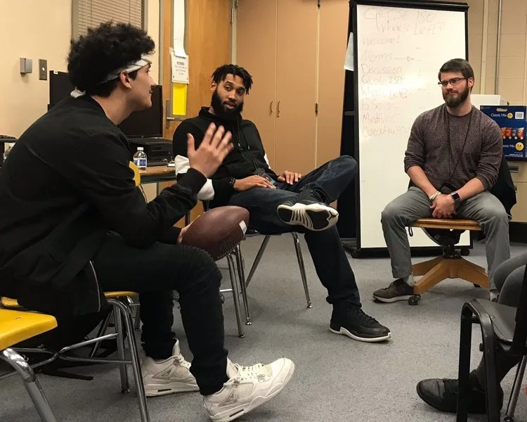 Two CHOOSE 180 staff sitting speaking with a program participant