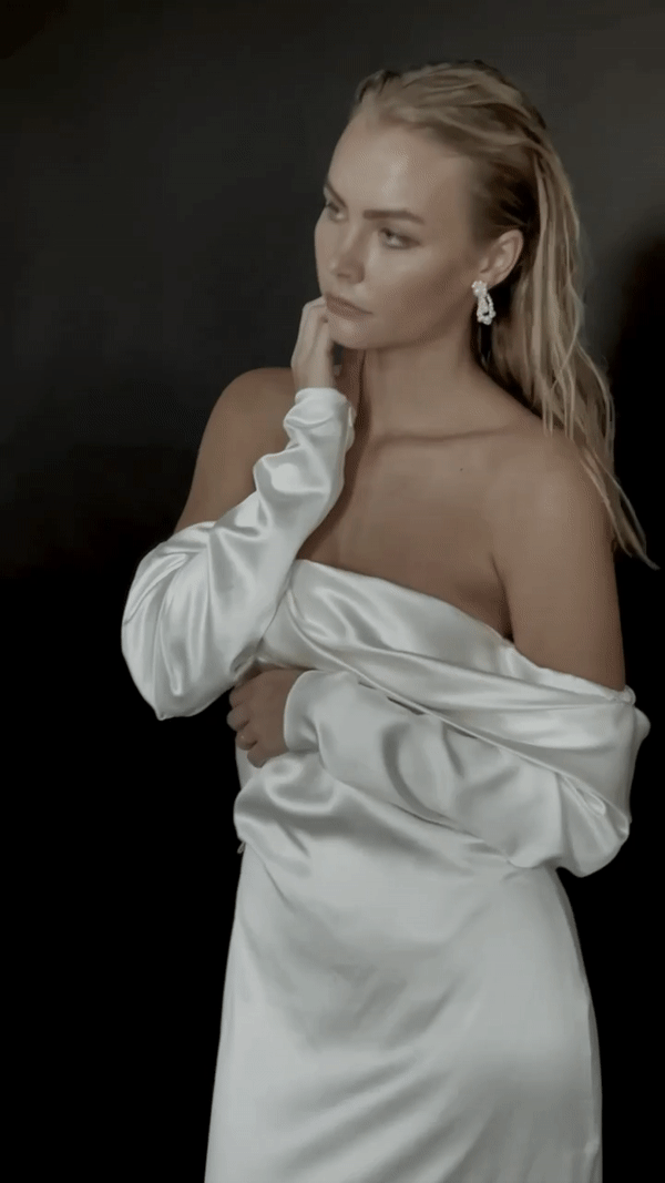 Video of model wearing silk off the shoulder gown and pearl teardrop earrings with clusters of varying sized pearls and a golden exposed wire bra structure with gold floral details.