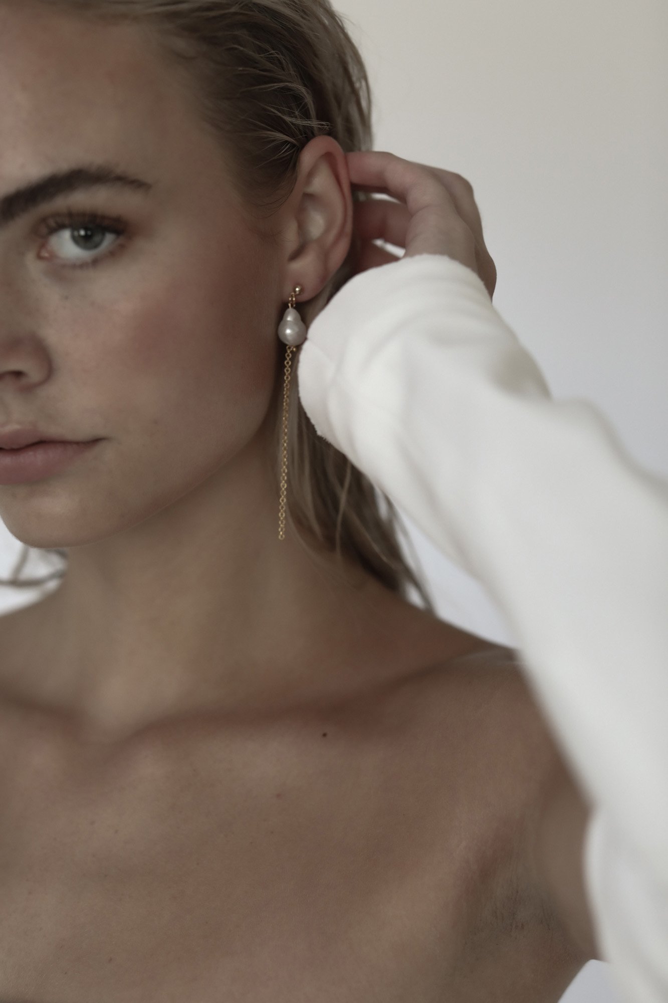  a baroque pearl chain earring styled on a clean fresh faced model in a modern bridal shoot. 