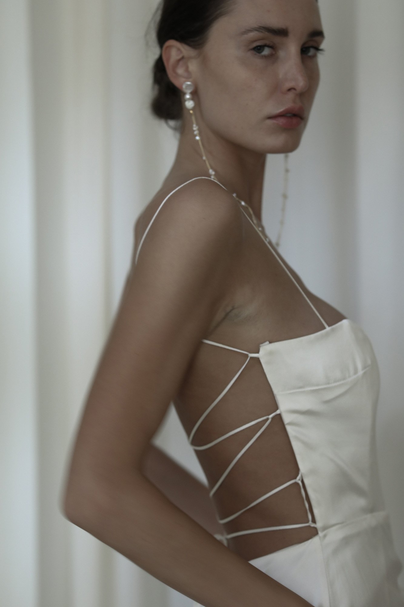  freshwater pearl strand earrings styled on a modern bride wearing a strappy silk wedding dress with modern low bun hairstyle. 