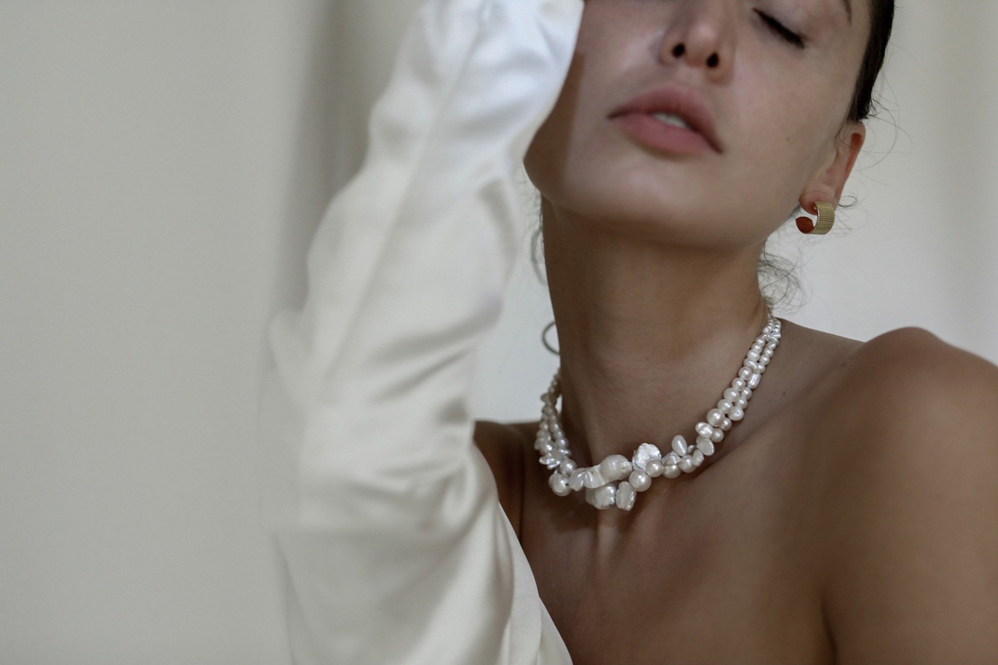  a modern pearl necklace styled with gold earrings in a silk wedding dress in the a.b. ellie studio. 
