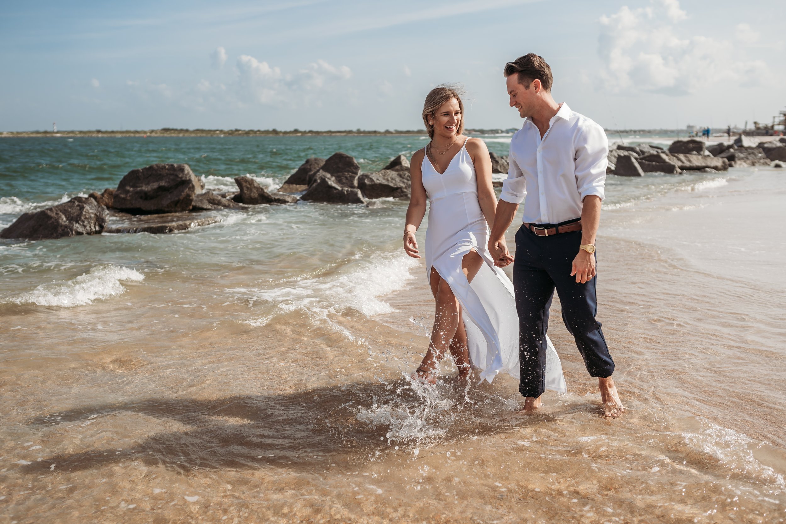 Couple walking through the surf in coordinated white and navy outfits