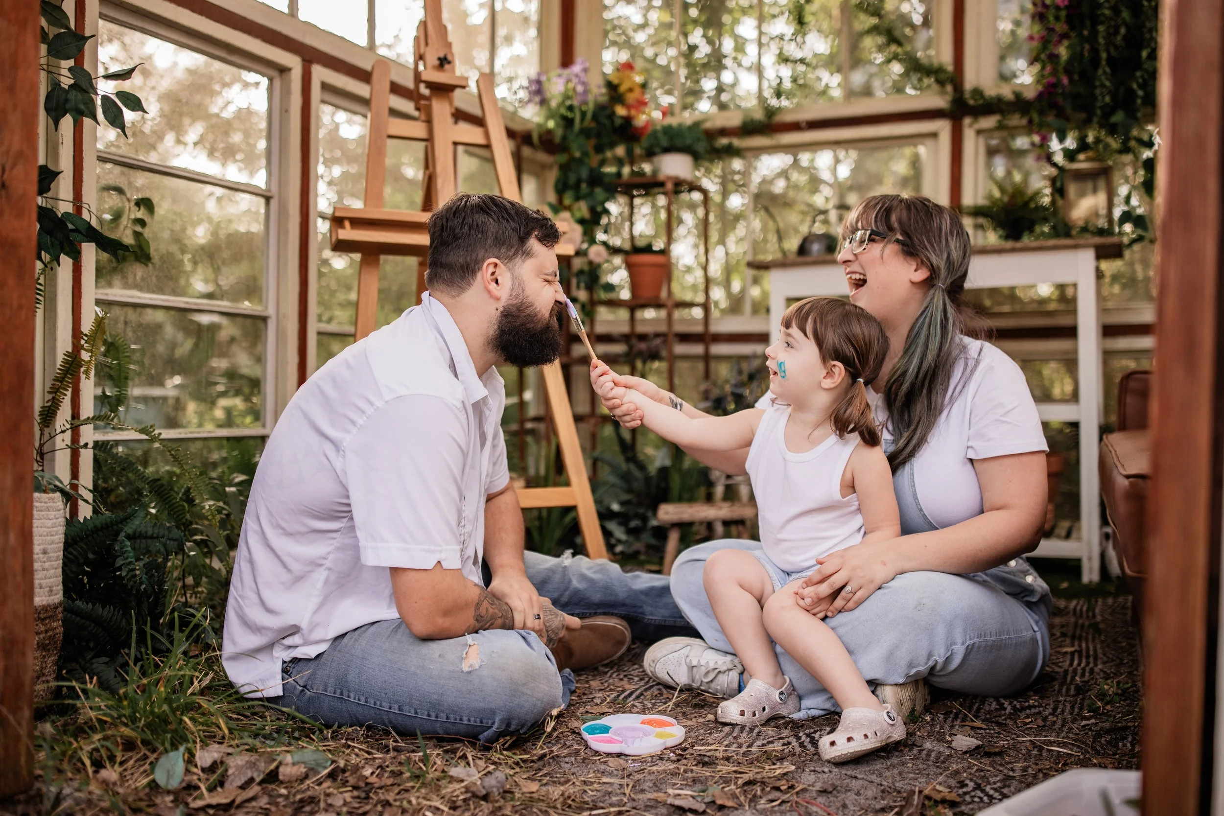 Family painting together inside greenhouse during lifestyle session in Northside Jacksonville Florida